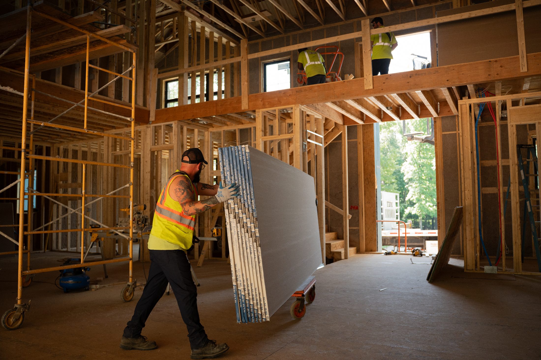 New custom home under construction with drywall being delivered by boom truck
