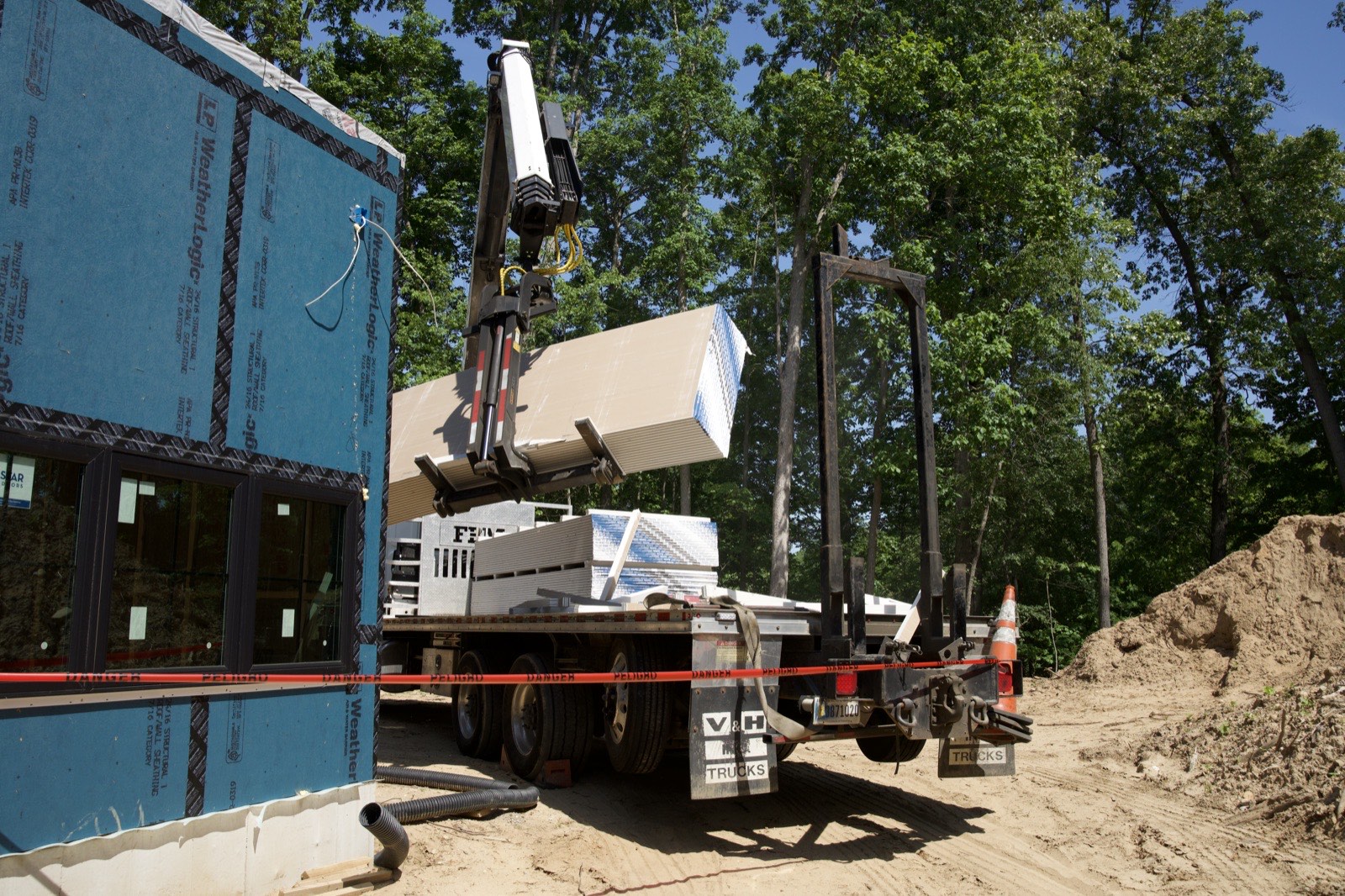 Boom crane lifting a bundle of drywall to a new home