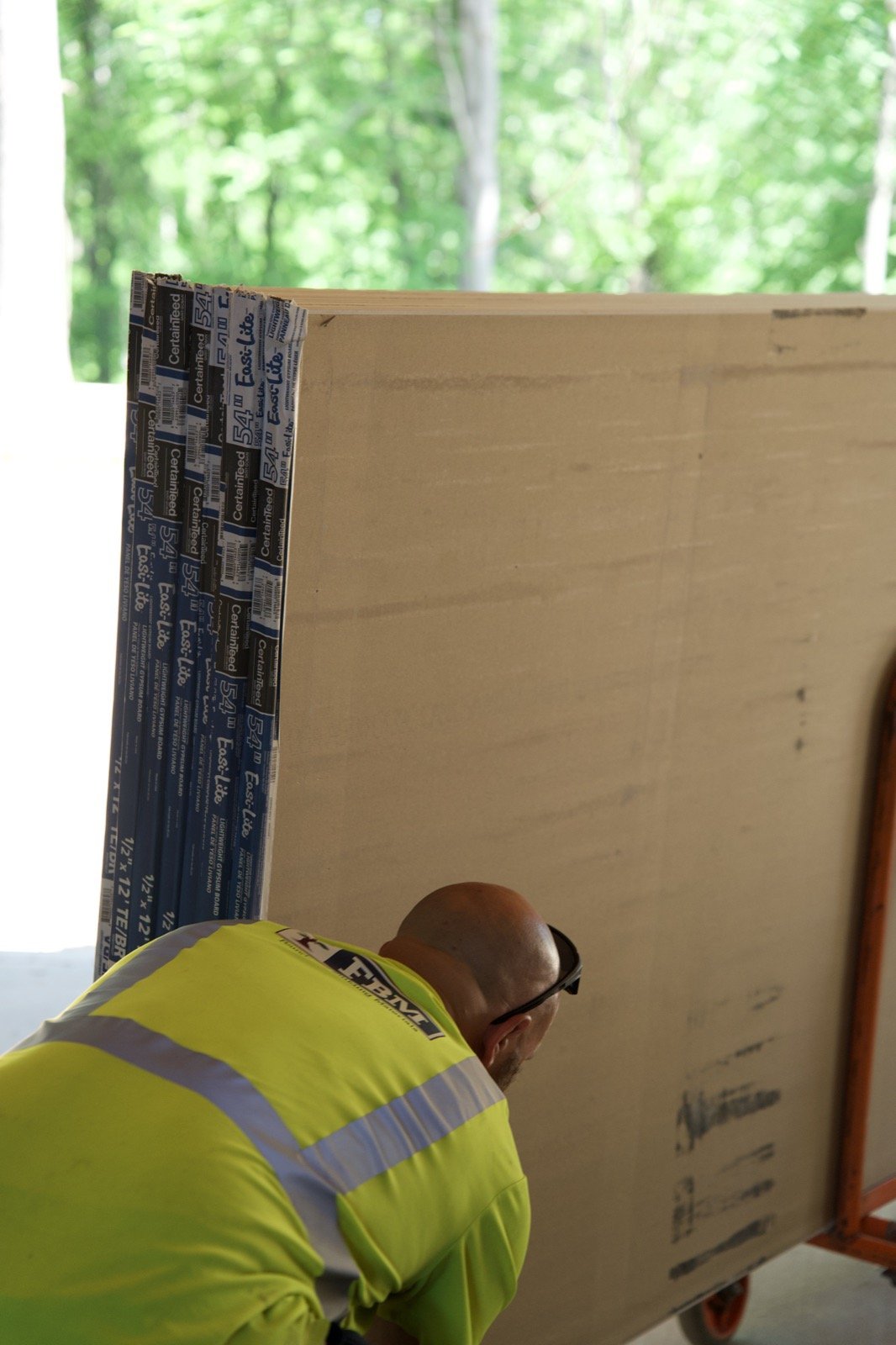 Worker steadying a stack of gypsum board